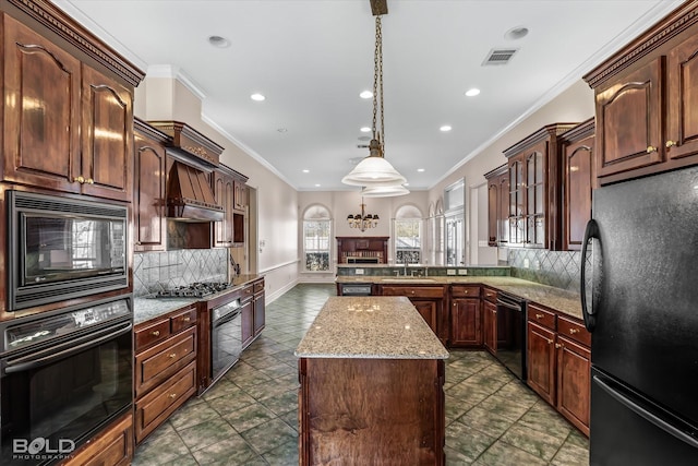 kitchen with backsplash, black appliances, sink, decorative light fixtures, and a kitchen island