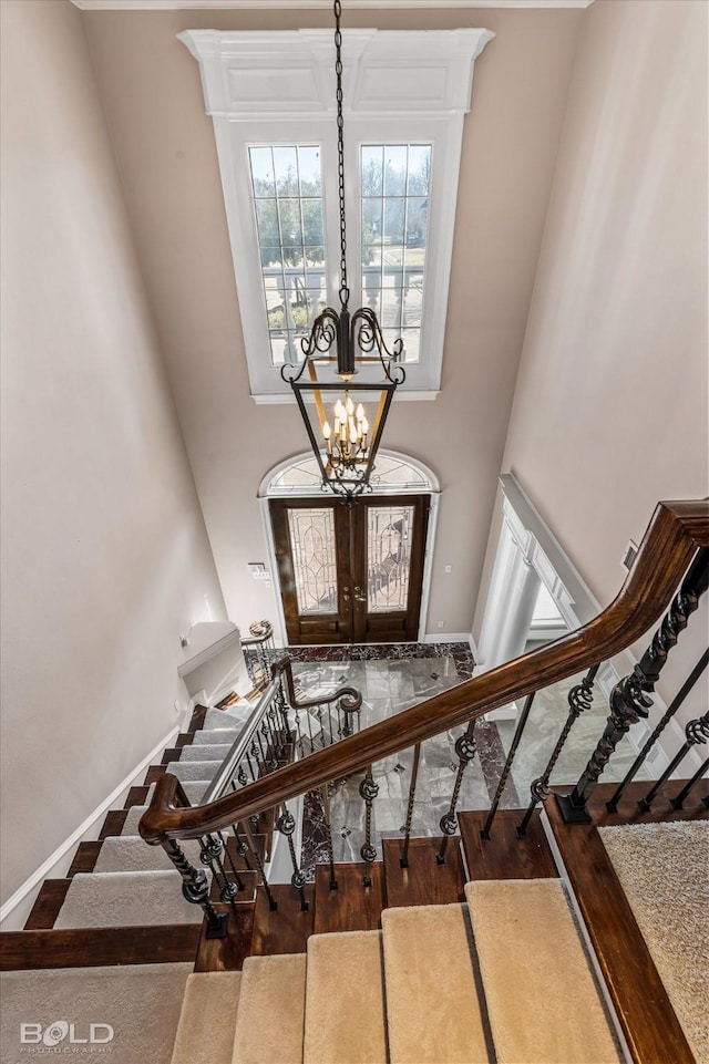 staircase featuring wood-type flooring, a towering ceiling, and an inviting chandelier