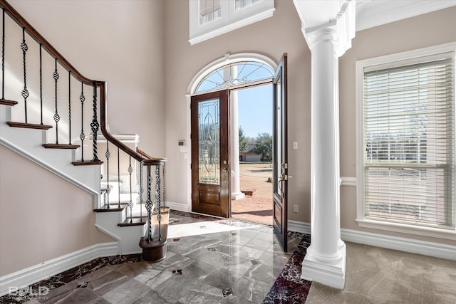 foyer featuring ornate columns and crown molding