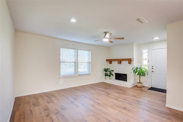 unfurnished living room with a brick fireplace, ceiling fan, and light hardwood / wood-style flooring