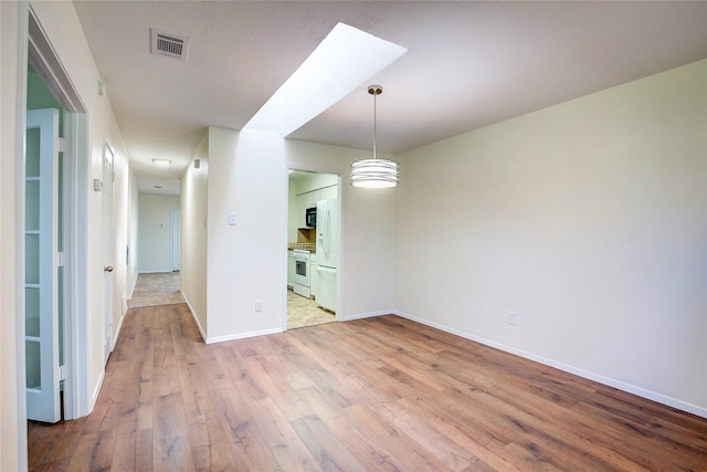 unfurnished dining area featuring a skylight and light hardwood / wood-style flooring