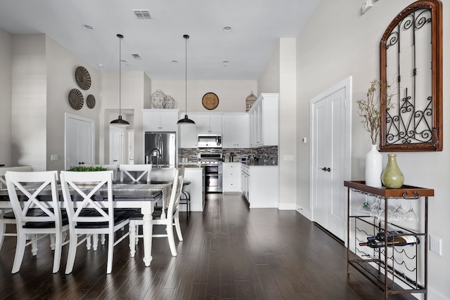 dining space featuring a towering ceiling and dark hardwood / wood-style floors