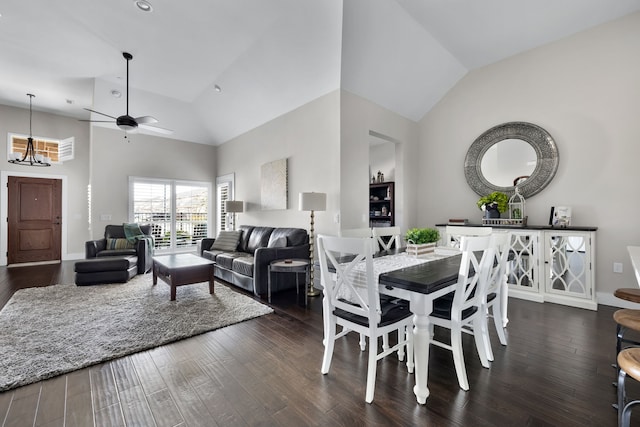 dining area with ceiling fan with notable chandelier, dark hardwood / wood-style flooring, and high vaulted ceiling