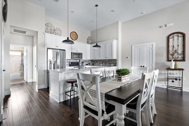 dining space featuring a high ceiling and dark hardwood / wood-style floors