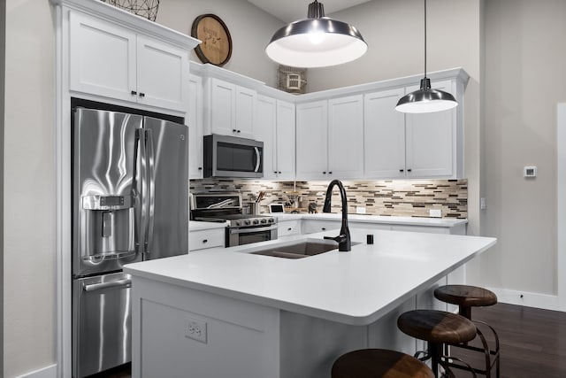 kitchen with stainless steel appliances, an island with sink, hanging light fixtures, and white cabinets