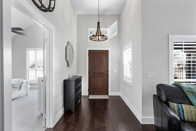 entrance foyer with ceiling fan with notable chandelier and dark wood-type flooring