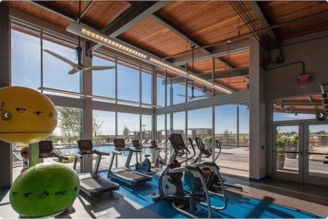 gym with french doors, wood ceiling, a towering ceiling, expansive windows, and ceiling fan