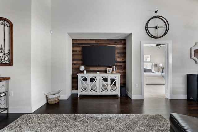 living room with ceiling fan, dark hardwood / wood-style flooring, and wood walls