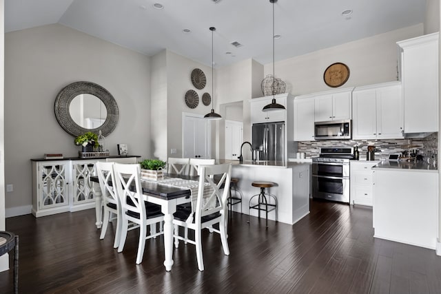 dining room with dark wood-type flooring, sink, and high vaulted ceiling