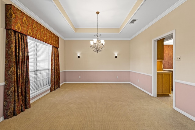 spare room featuring a tray ceiling, ornamental molding, light colored carpet, and an inviting chandelier