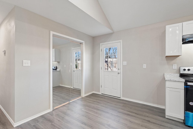 kitchen featuring range with electric cooktop, white cabinets, lofted ceiling, and light wood-type flooring