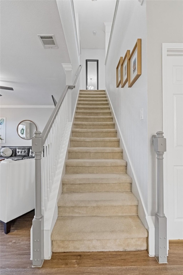 staircase featuring crown molding and hardwood / wood-style floors