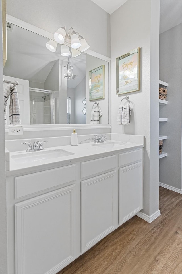 bathroom with an inviting chandelier, hardwood / wood-style floors, vaulted ceiling, a shower with door, and vanity