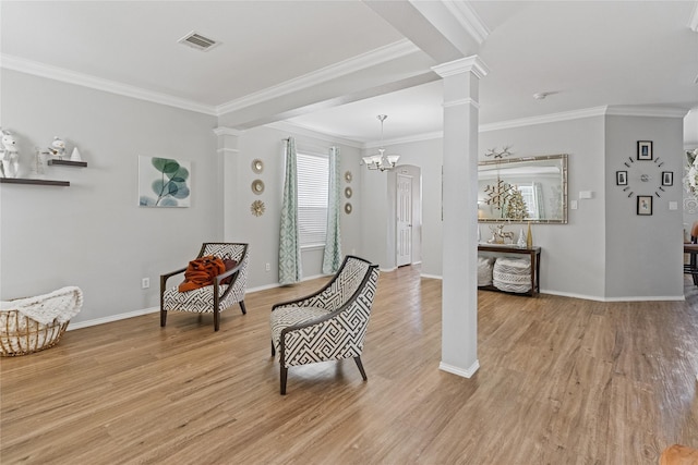 living area with an inviting chandelier, ornate columns, crown molding, and light hardwood / wood-style flooring