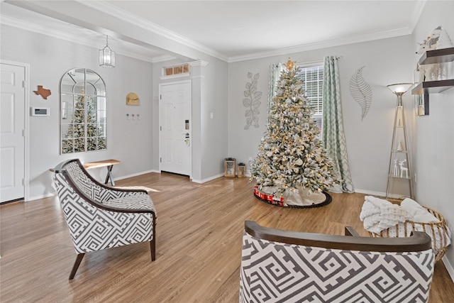 sitting room featuring light wood-type flooring, an inviting chandelier, and crown molding