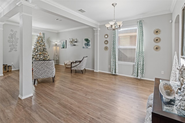 sitting room featuring hardwood / wood-style floors, an inviting chandelier, crown molding, and decorative columns