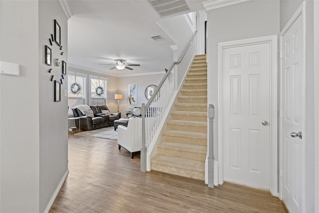 stairway featuring wood-type flooring, ceiling fan, and crown molding