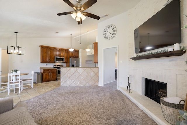 carpeted living room featuring a brick fireplace, vaulted ceiling, and ceiling fan with notable chandelier