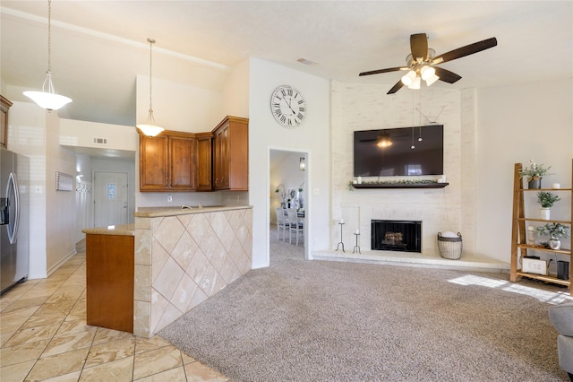 kitchen with a tile fireplace, light carpet, stainless steel fridge with ice dispenser, hanging light fixtures, and ceiling fan