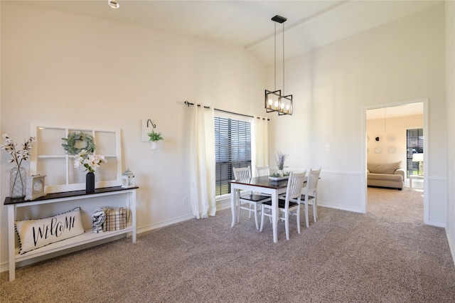 carpeted dining room with an inviting chandelier and high vaulted ceiling