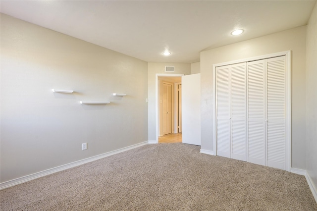 unfurnished bedroom featuring light colored carpet and a closet