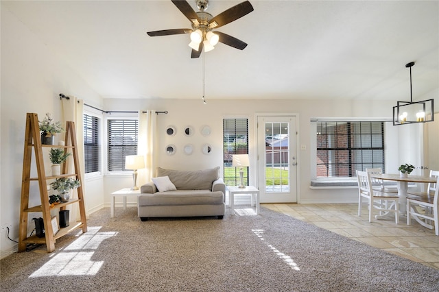 carpeted living room featuring ceiling fan with notable chandelier and lofted ceiling