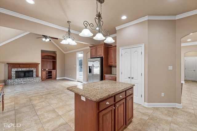 kitchen featuring light stone countertops, stainless steel refrigerator with ice dispenser, a kitchen island, and crown molding