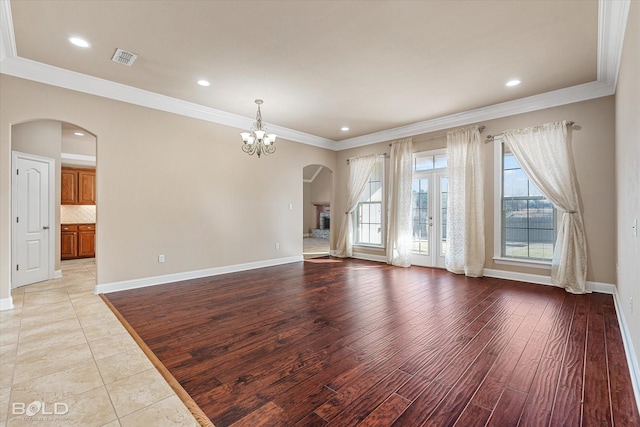 unfurnished living room with ornamental molding, a healthy amount of sunlight, an inviting chandelier, and light hardwood / wood-style floors