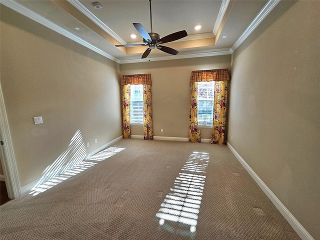 carpeted spare room with ceiling fan, ornamental molding, and a tray ceiling