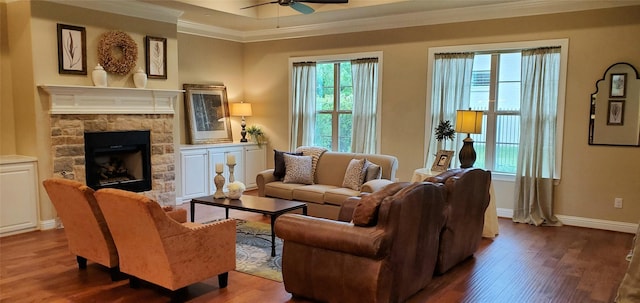 living room with crown molding, a stone fireplace, and hardwood / wood-style flooring