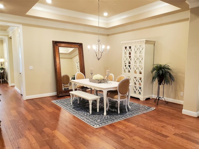 dining space featuring crown molding, hardwood / wood-style flooring, a raised ceiling, and an inviting chandelier