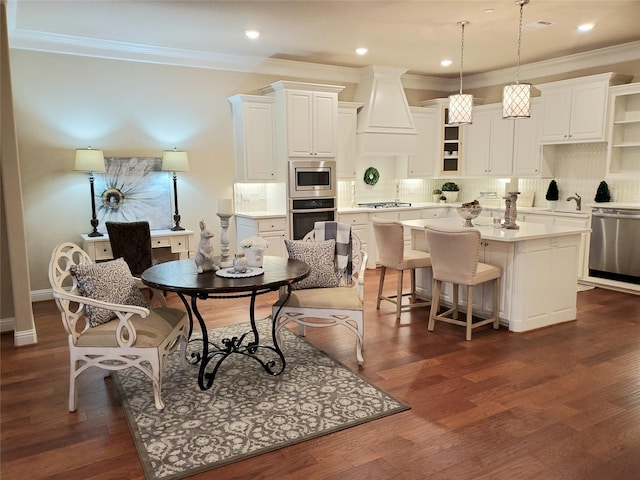 kitchen with a kitchen island, appliances with stainless steel finishes, white cabinetry, hanging light fixtures, and dark wood-type flooring