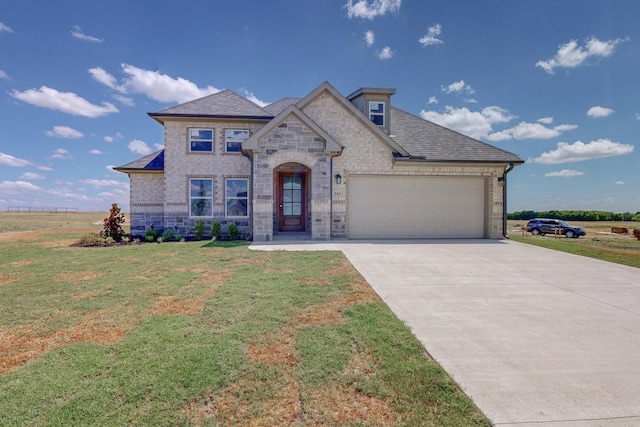 french provincial home featuring a front yard, roof with shingles, a garage, stone siding, and driveway