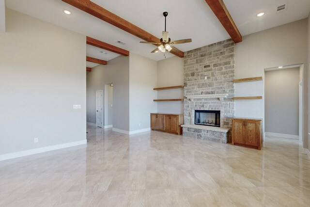 unfurnished living room featuring a ceiling fan, visible vents, baseboards, a stone fireplace, and beamed ceiling