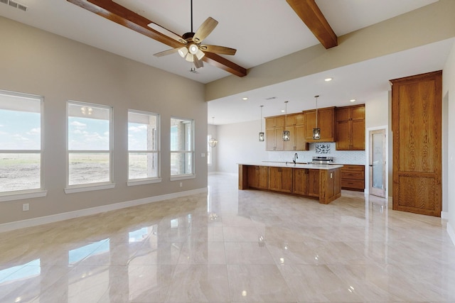 kitchen featuring baseboards, open floor plan, light countertops, brown cabinetry, and a ceiling fan