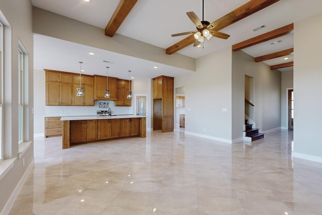 kitchen featuring baseboards, brown cabinets, ceiling fan, and light countertops