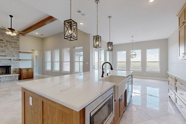 kitchen with backsplash, a kitchen island with sink, hanging light fixtures, ceiling fan, and beamed ceiling