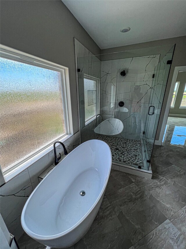 bathroom with a marble finish shower, a freestanding bath, and marble finish floor