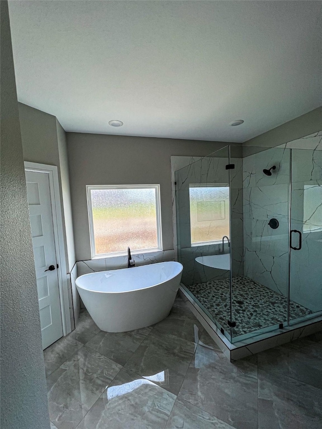 bathroom with marble finish floor, a marble finish shower, and a freestanding bath