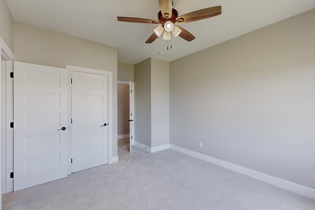 unfurnished bedroom featuring baseboards, light carpet, and a ceiling fan