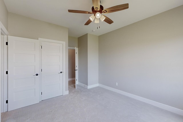 unfurnished bedroom with ceiling fan, light carpet, and a closet