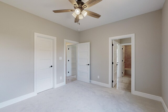 unfurnished bedroom featuring light carpet, a ceiling fan, ensuite bathroom, and baseboards