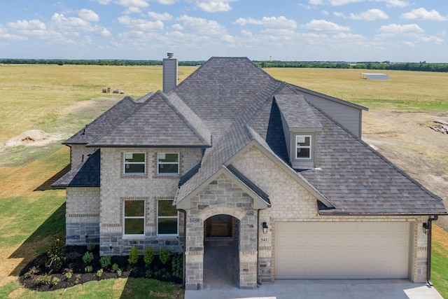 view of front of house with a front yard, driveway, roof with shingles, and a chimney