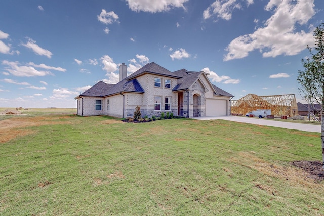 french country home with brick siding, a front lawn, a chimney, driveway, and an attached garage