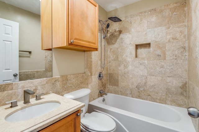 full bathroom with tile walls, backsplash, tiled shower / bath combo, vanity, and toilet