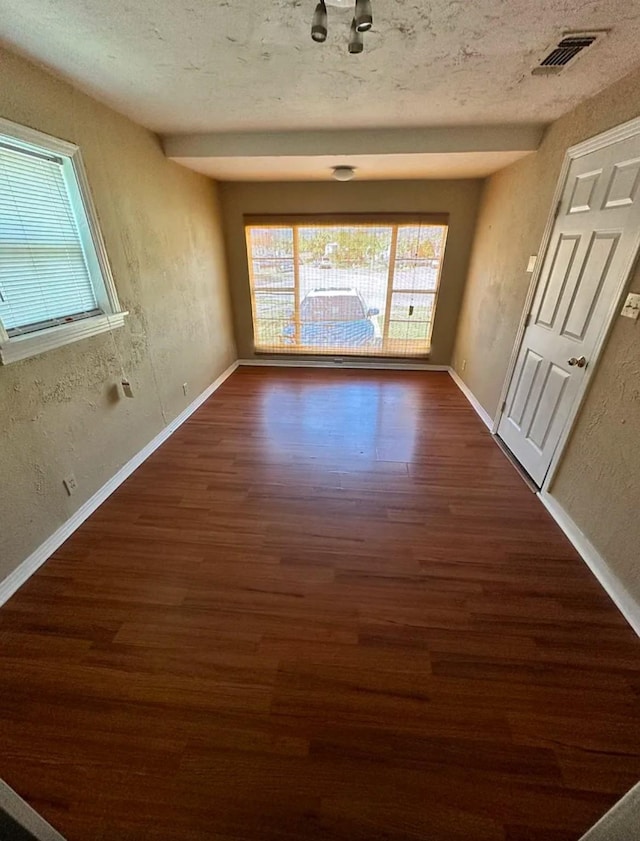 empty room with a textured ceiling and dark hardwood / wood-style flooring