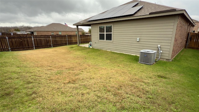 back of house featuring cooling unit, a yard, and solar panels