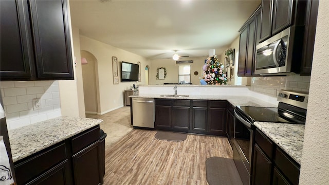 kitchen with sink, decorative backsplash, light stone counters, light hardwood / wood-style floors, and stainless steel appliances