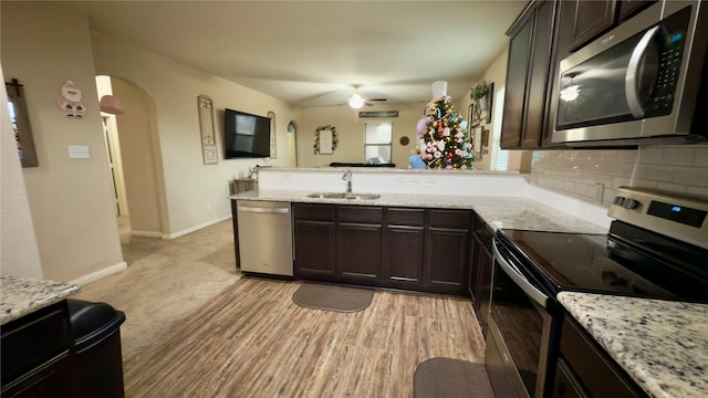 kitchen with dark brown cabinetry, stainless steel appliances, kitchen peninsula, and sink