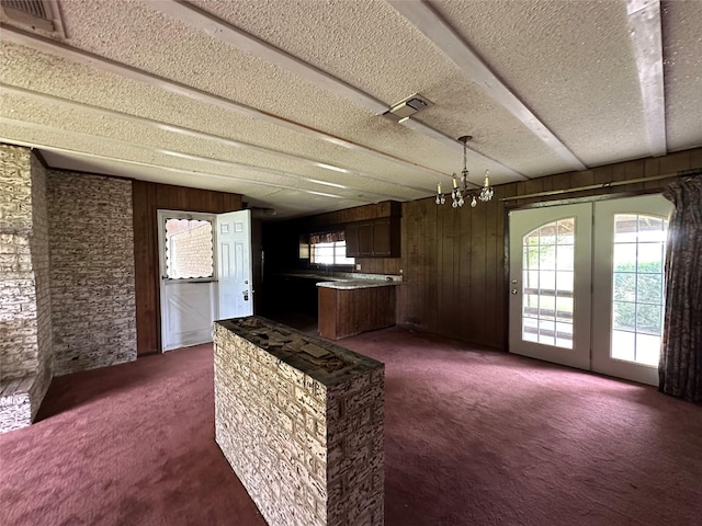 kitchen featuring hanging light fixtures, dark carpet, dark brown cabinets, a textured ceiling, and an inviting chandelier